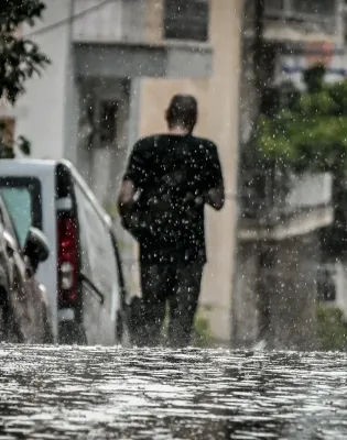 Άνδρας περπατάει μέσα στην καταιγίδα την ώρα που βρέχει