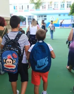 Μαθητές με τις τσάντες τους συνοδεύονται από πατέρα προς το σχολείο
