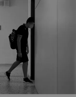 Μαθητής περπατάει μέσα σε σχολείο σε ασπρόμαυρη φωτογραφία