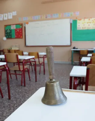 Τάξη σχολείου με κουδούνι πάνω σε θρανίο