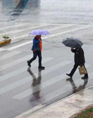 Βροχές και καταιγίδες στην Αθήνα με κόσμο να περνάει τον δρόμο με ομπρέλες