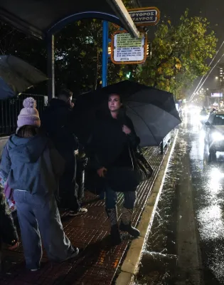 Κόσμος με ομπρέλες σε στάση λεωφορείου στην Αττική ενώ ειναι καταιγίδα σε ελέλιξη