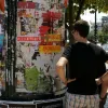 φοιτητής ψάχνει για σπίτι κοιτώντας αγγελίες στο δρόμο