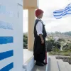 Μαθητής σε σχολείο με παραδοσιακή στολή και την Ελληνική σημαία