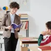εκπαιδευτικός σε τάξη κοιτάει ένα ανοικτό βιβλίο