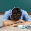 Δάσκαλος κουρασμένος ξαπλώνει πάνω στα χέρια του στην έδρα 