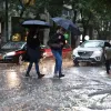 κακοκαιρία, ΕΜΥ, άνθρωποι με ομπρέλες προχωρούν σε πλημμυρισμένο δρόμο 