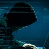 Χάκερ με κουκούλα σε υπολογιστή με δεδομένα στην οθόνη