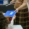 Δασκάλα δίνει τετράδιο σε μικρή μαθήτρια στην τάξη