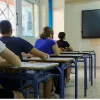 Μαθητές δίνουν πανελλήνιες, κάθονται σε θρανία και τους μιλάει δασκάλα