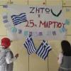 Μαθητές με ελληνική σημαία κοιτάνε πινακίδα που γράφει ζήτω η 25η Μαρτίου