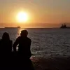 Ζευγάρι κοιτάει το ηλιοβασίλεμα στη θάλασσα