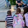 Μαθητές με σχολική τσάντα κάθονται και μιλάνε