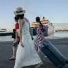 Γυναίκες κρατάνε βαλίτσες στο λιμάνι και πηγαίνουν διακοπές