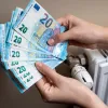 Χέρια μετράνε χρήματα για το επίδομα θέρμανσης δίπλα σε καλοριφέρ