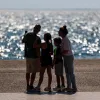 Οικογένεια που θα πάρει το έκτακτο επίδομα παιδιού κοιτάζει τη θάλασσα αγκαλιά