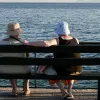 Γυναίκες συνταξιούχοι κάθονται σε παγκάκι και κοιτάνε τη θάλασσα το καλοκαίρι