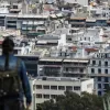 Γυναίκα κοιτάει πανοραμικά τα σπίτια στην Αθήνα από λόφο