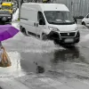 Γυναίκα περπατάει με ομπρέλα εν μέσω κακοκαιρίας ενώ αμάξια είναι σε βρεγμένο δρόμο