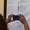 Γυναίκα φωτογραφίζει πίνακα με τα αποτελέσματα στις Πανελλαδικές Εξετάσεις