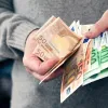 Άνδρας μετράει χρήματα και ευρώ με τα χέρια του