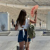 Κοπέλα κάνει αέρα με βεντάλια έξω από το παναθηναικό στάδιο λόγω καύσωνα