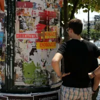 φοιτητής ψάχνει για σπίτι κοιτώντας αγγελίες στο δρόμο