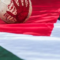 Μπάλα ποδοσφαίρου βαμμένη με αίμα πάνω σε σημαία της Παλαιστίνης