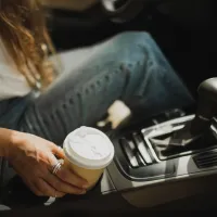 Γυναικείο χέρι κρατάει καφέ μέσα σε αμάξι 