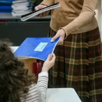 Δασκάλα δίνει τετράδιο σε μικρή μαθήτρια στην τάξη