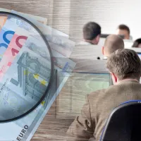 Χρήματα σε ευρώ, μεγεθυντικός φακός και υπάλληλοι σε υπολογιστές