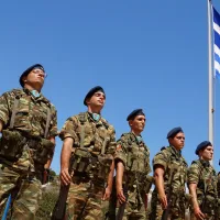 Στρατιώτες, φαντάροι σε στάση προσοχής με φόντο την ελληνική σημαία