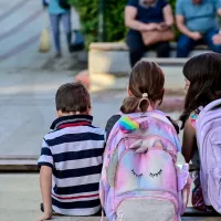 Μαθητές με σχολική τσάντα κάθονται και μιλάνε