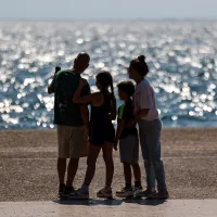 Οικογένεια που θα πάρει το έκτακτο επίδομα παιδιού κοιτάζει τη θάλασσα αγκαλιά