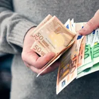 Άνδρας μετράει χρήματα και ευρώ με τα χέρια του