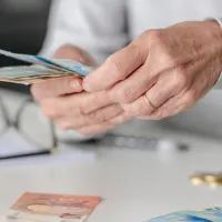 Γυναίκα συνταξιούχους μετράει χρήματα συνταξιοδότησης – αλλαγές στη φορολογία για πρόωρη σύνταξη και ΤΕΑ