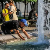 Άνδρας δροσίζεται εν μέσω καύσωνα στο σιντριβάνι στο Σύνταγμα