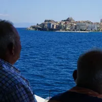 Δύο συνταξιούχοι κάθονται σε παγκάκι και κοιτάζουν τη θάλασσα το καλοκαίρι