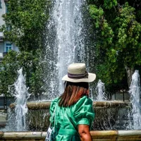 Γυναίκα περπατάει μπροστά από συντριβάνι εν μέσω καύσωνα