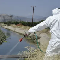 Άνδρας του ΕΟΔΥ με στολή ψεκάζει σε στάσιμα νερά για κουνούπια