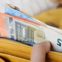 Χέρια ανθρώπου ανοίγουν πορτοφόλι γεμάτο χαρτονομίσματα ευρώ