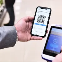 Ανδρικά χέρια κρατάνε κινητό με barcode μέσα από την εφαρμογή του ΕΡΓΑΝΗ