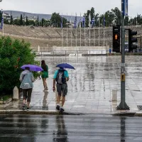 Άνθρωποι με ομπρέλες στο Καλλιμάρμαρο ενώ βρέχει στην Αττική