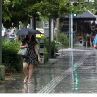 Γυναίκα κρατάει ομπρέλα ενώ βρέχει στην Αττική