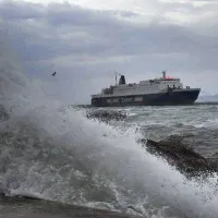 Πλοίο της γραμμής περνάει μπροστά από λιμάνι ενώ κύμα σκάει στην προβλήτα