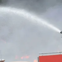 Πυροσβέστης πάνω σε όχημα της Πυροσβεστικής σβήνει με μάνικα φωτιά 