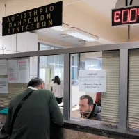 Εσωτερικό δημόσιας υπηρεσίας με πολίτη σε γκισέ που φέρει την επιγραφή «Λογιστήριο Πληρωμών Συντάξεων» και ψηφιακό πίνακα προτεραιότητας