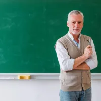 Εκπαιδευτικός μπροστά από πίνακα κοιτάζει την κάμερα ενώ περιμένει το άνοιγμα του ΟΠΣΥΔ
