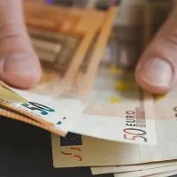 Ανδρικά χέρια που μετρούν χαρτονομίσματα ευρώ, σε άρθρο που αφορά τα ποσά και τις πληρωμές των συντάξεων