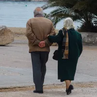Συνταξιούχοι περπατάνε στον δρόμο με φόντο τη θάλασσα